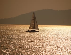 silhouette photo of sailboat on body of water thumbnail