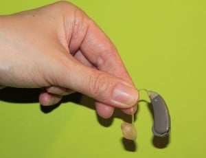 person left hand holding hearing aid thumbnail
