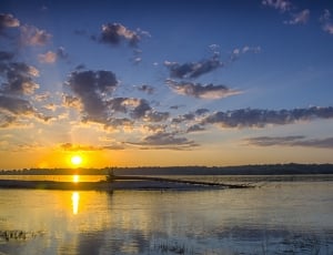 landscape photo of body of water and cumulus clouds during golden hour thumbnail