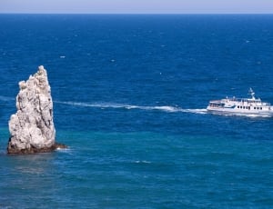 white cruise ship near gray rock formation in body of water thumbnail