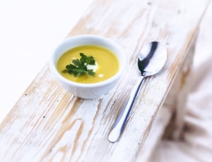 stainless steel spoon beside bowl with yellow soup thumbnail