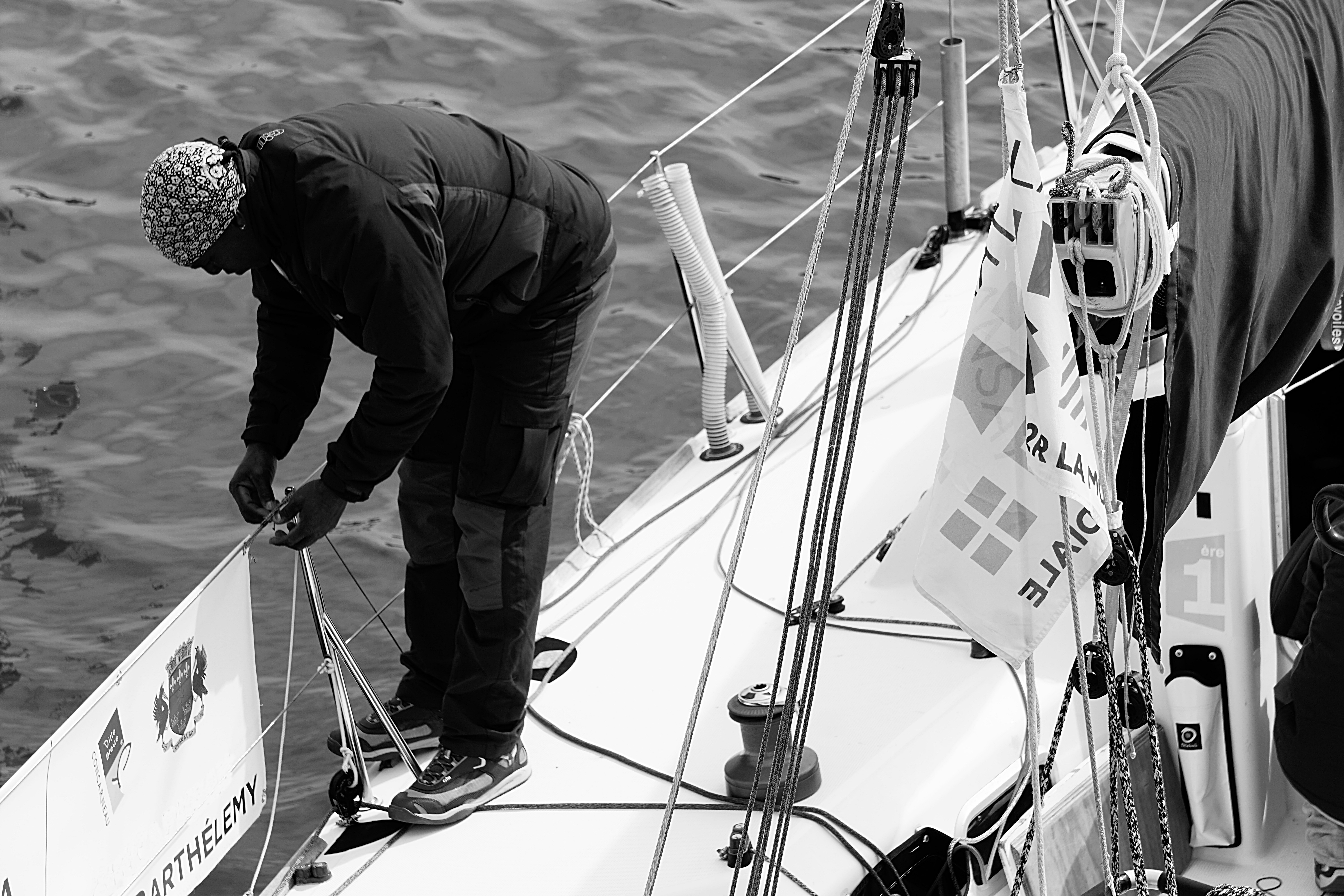 gray scale photo of man tying rope on boat