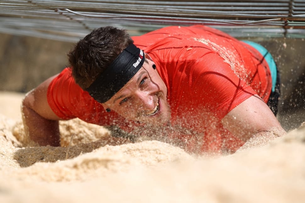 man in red crewneck shirt with black headband on sand crawling during daytime preview