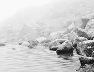 greyscale photo of rocks in body of water thumbnail
