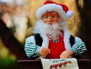 Santa Claus writing on paper doll selective focus photography thumbnail