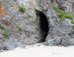 gray stone cave on white beach sand during daytime thumbnail
