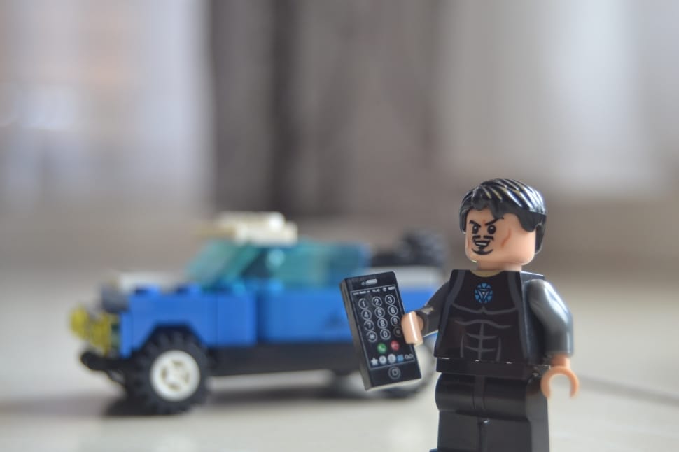 lego toy action figure holding remote next to blue lego vehicle preview