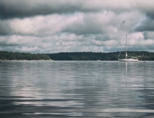 White Sailboat Across the Body of Water Under White and Gray Cloudy Sky thumbnail