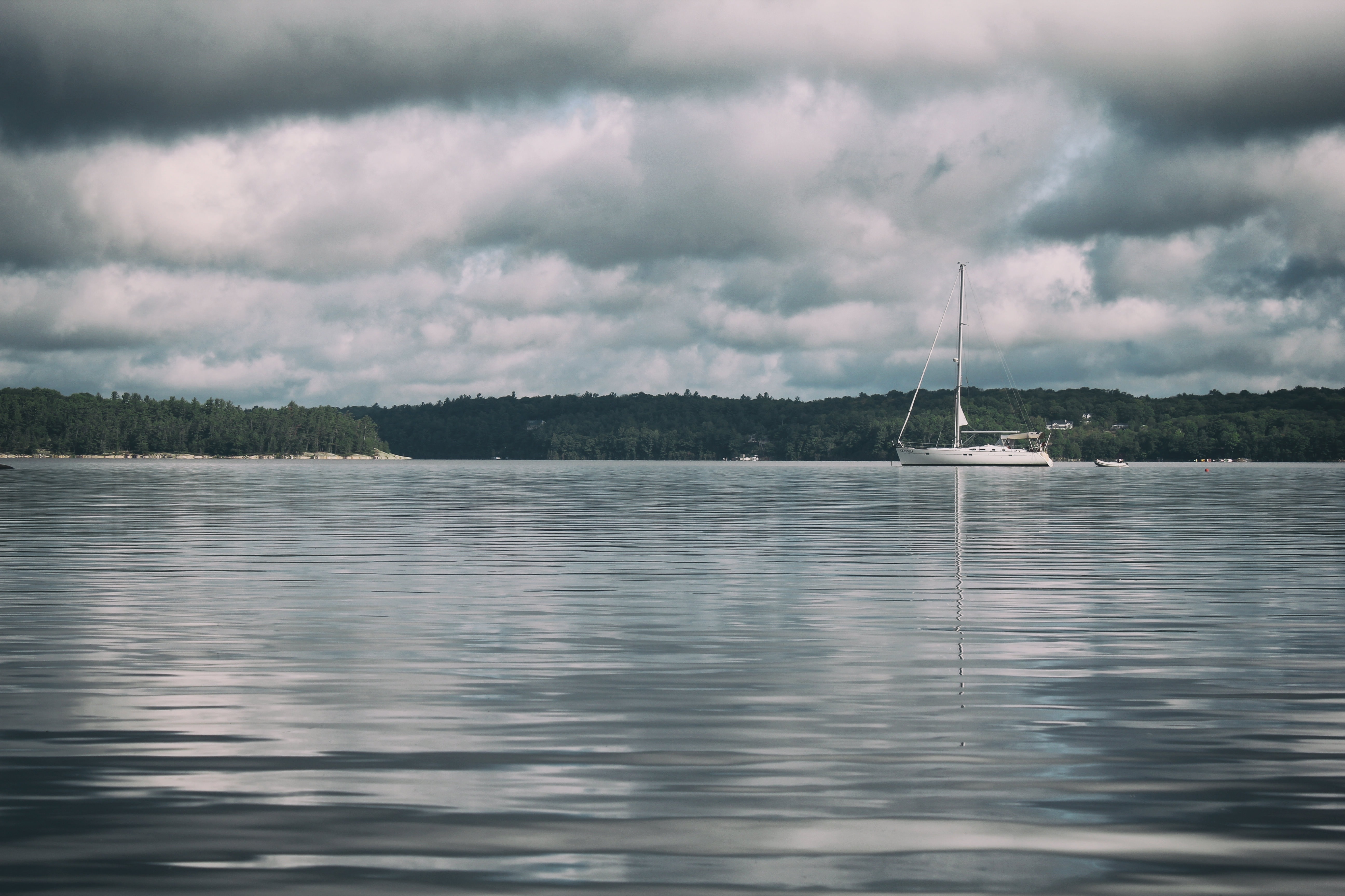 White Sailboat Across the Body of Water Under White and Gray Cloudy Sky