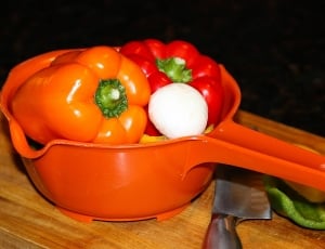 red and orange bell pepper on orange plastic dipper thumbnail
