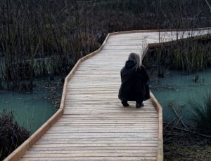 photography of woman squatting in brown wooden bridge thumbnail