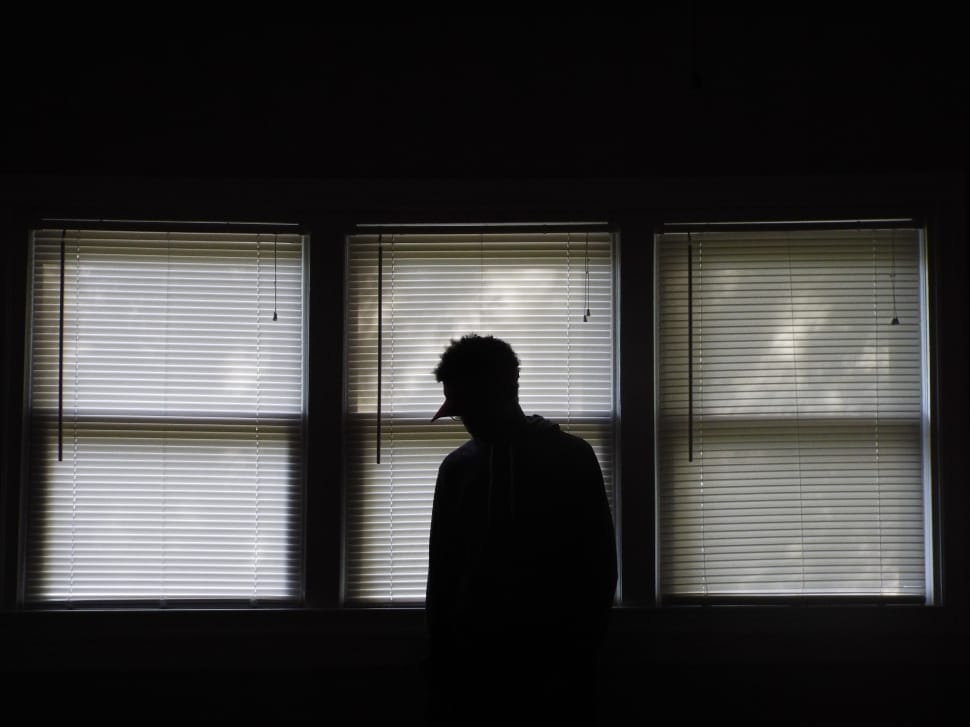 silhouette of a man beside window blinds during daytime preview