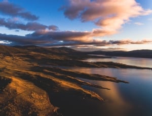 landscape photography of body of water and mountains thumbnail