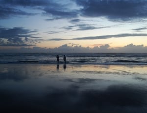 silhouette of two persons on sea during golden hour thumbnail