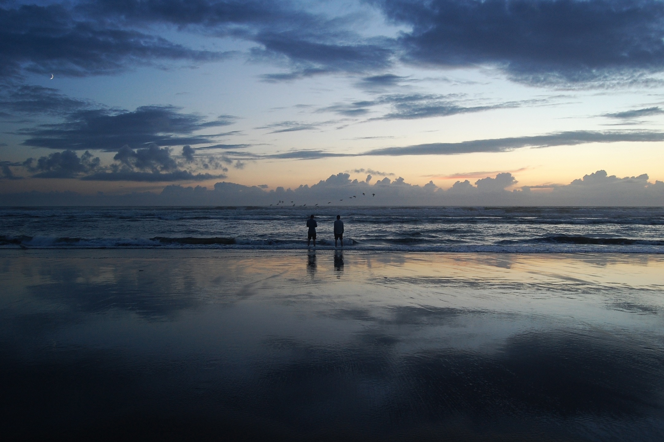 silhouette of two persons on sea during golden hour