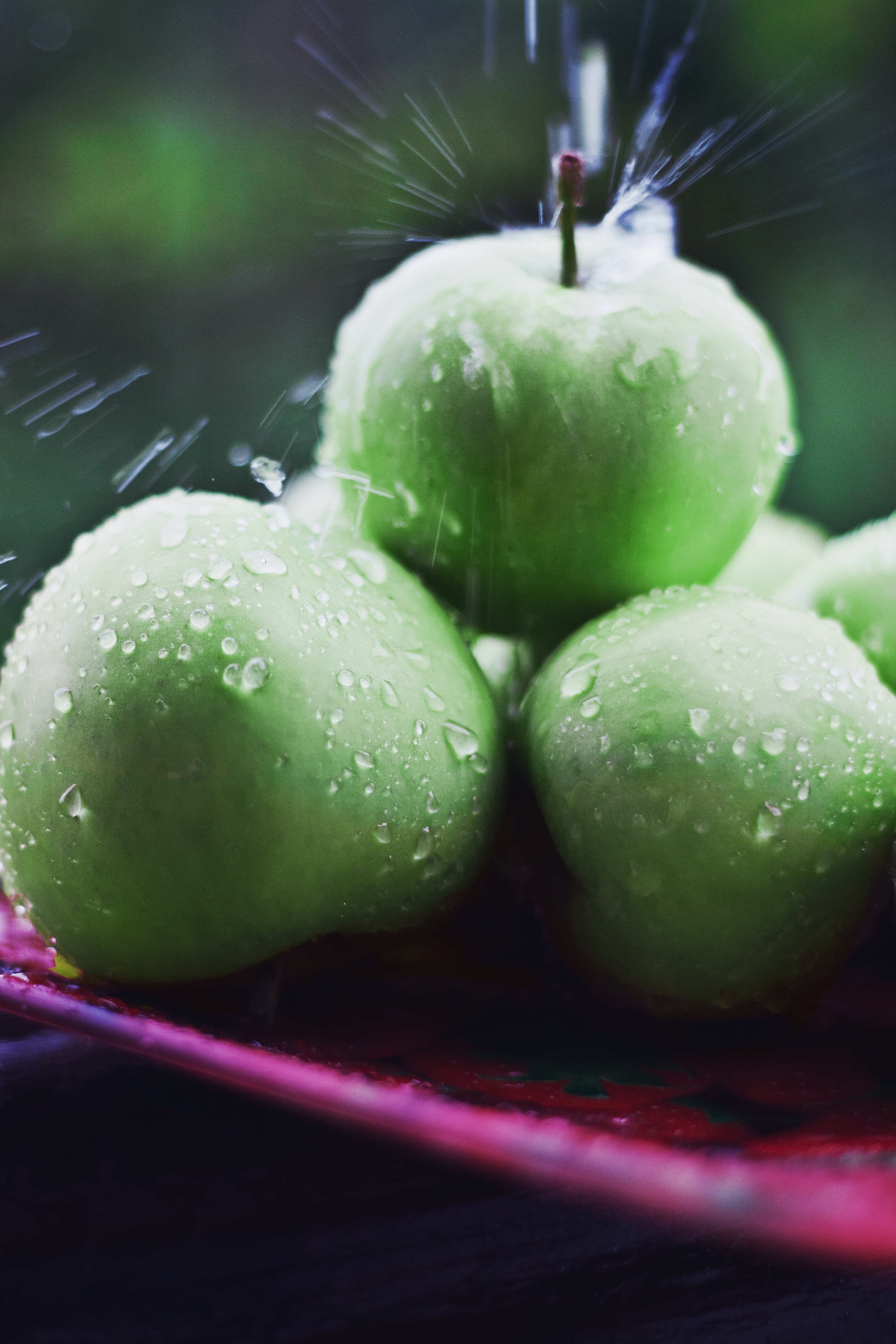wet green apples on pink tray