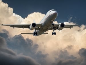 white airplane under gray cloudy sky thumbnail