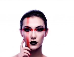 woman with black lisptick and eyeshadow with red cross print on face thumbnail