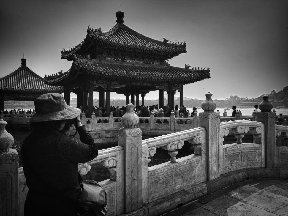 grayscale photo of woman in black long sleeve dress capturing picture of temple preview