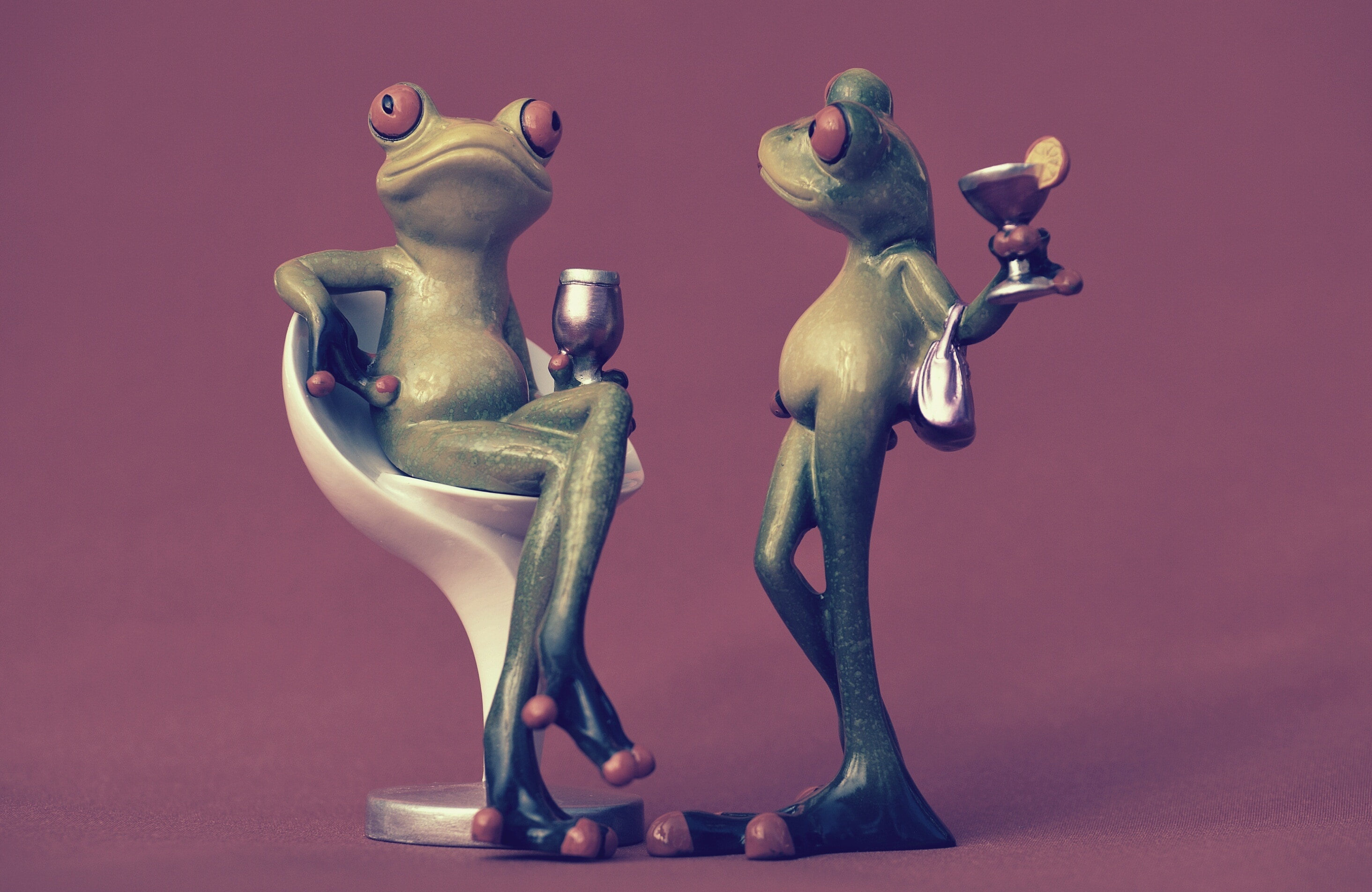 two green tree frogs holding a drinking glasses figurines